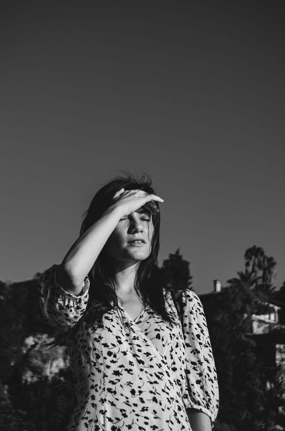 a black and white photo of a woman covering her eyes