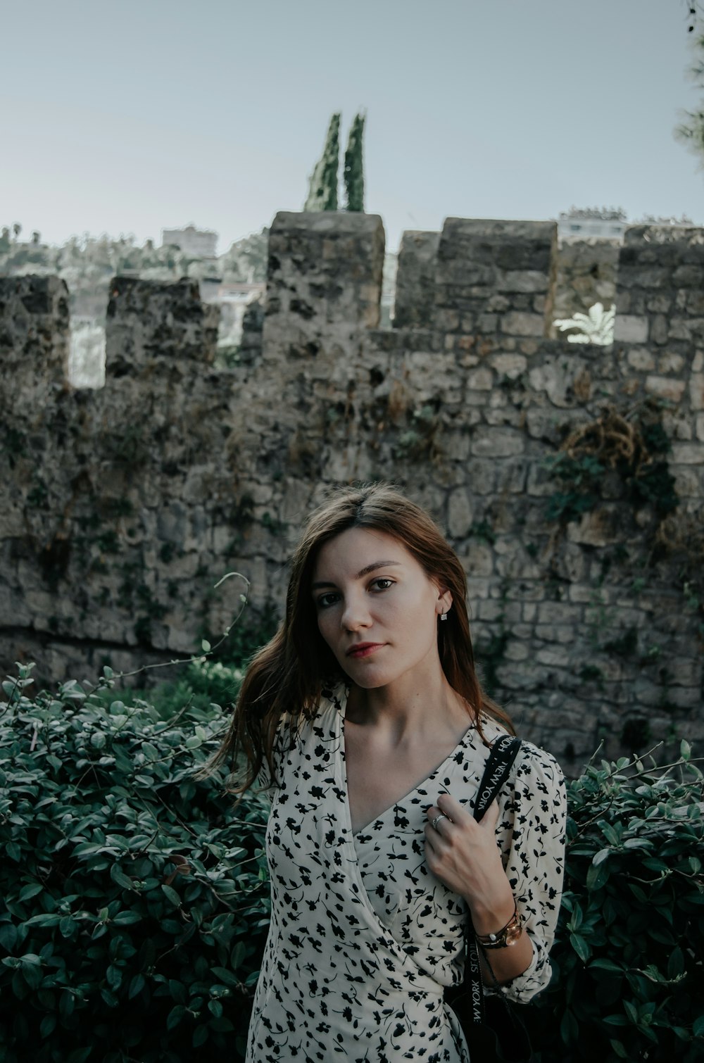 a woman standing in front of a stone wall