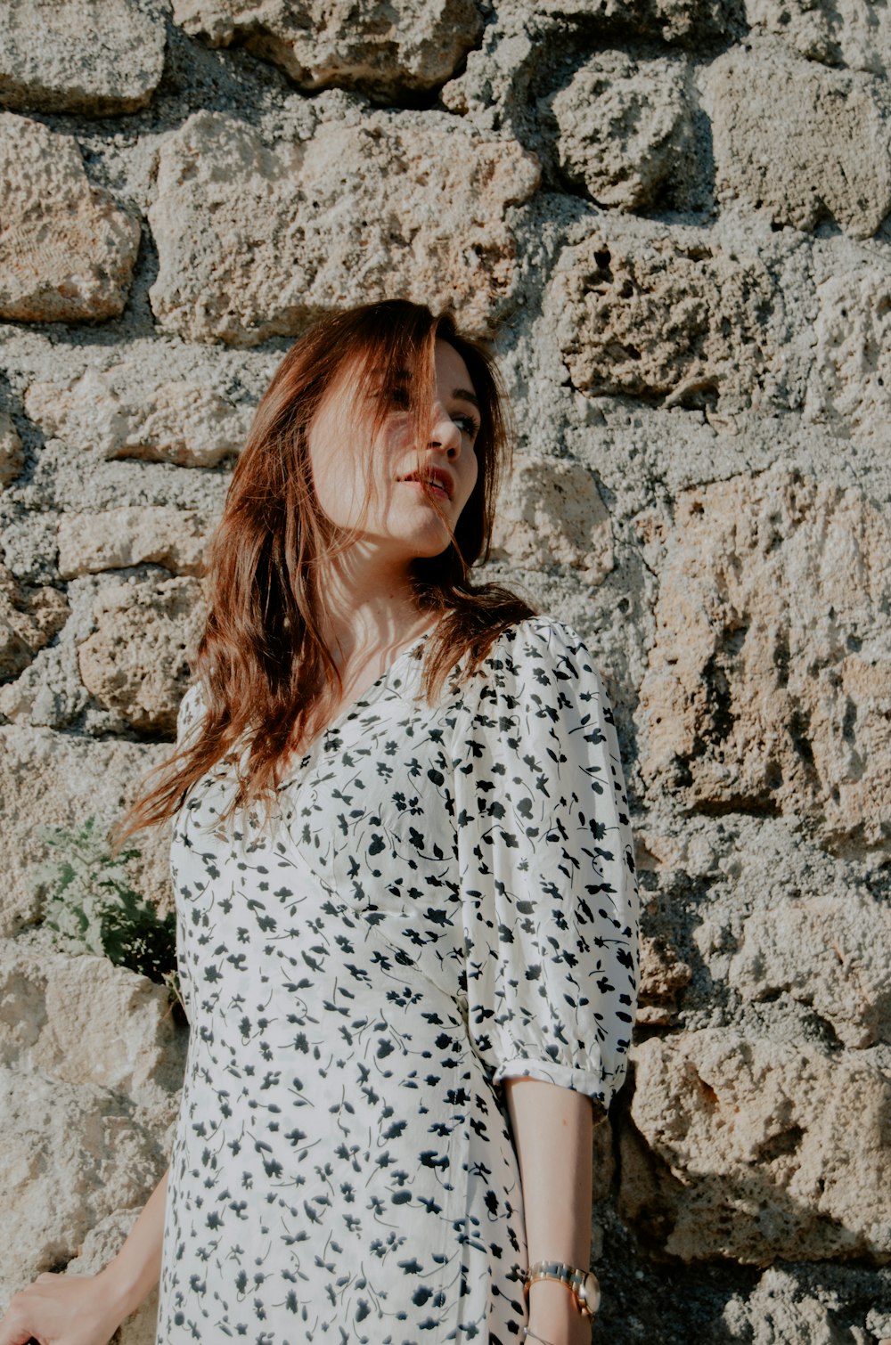 a woman standing in front of a stone wall