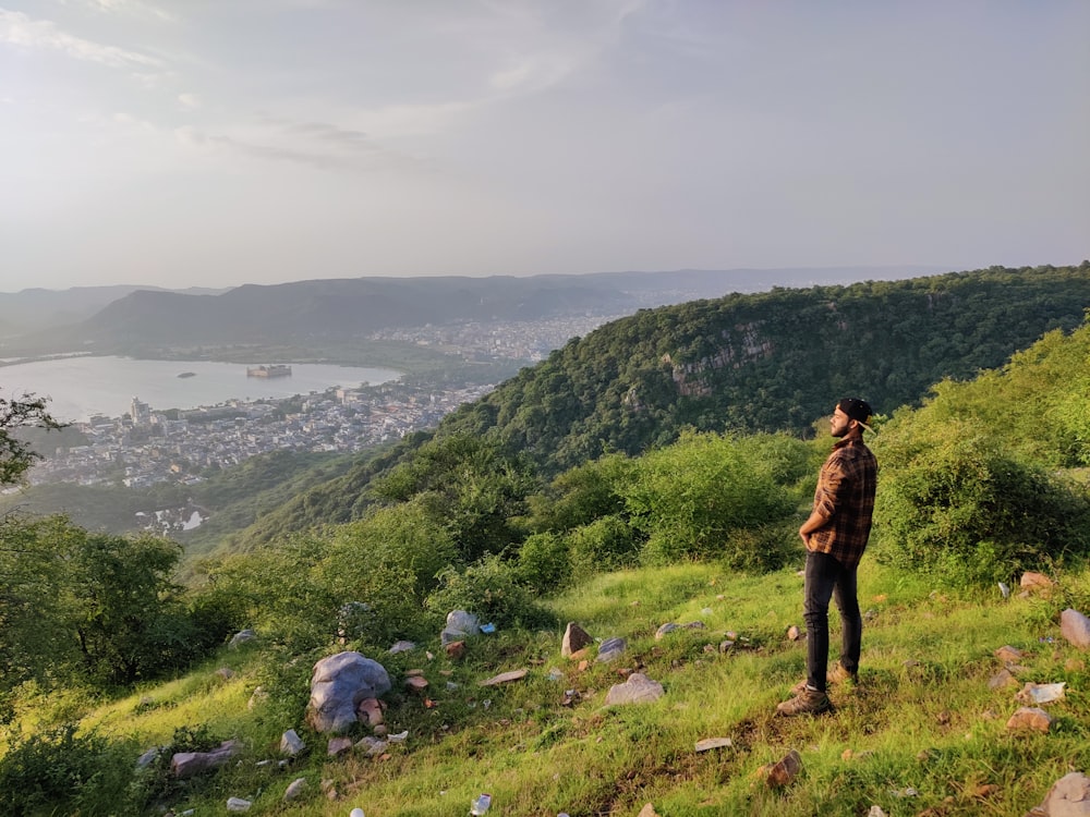 a man standing on top of a lush green hillside