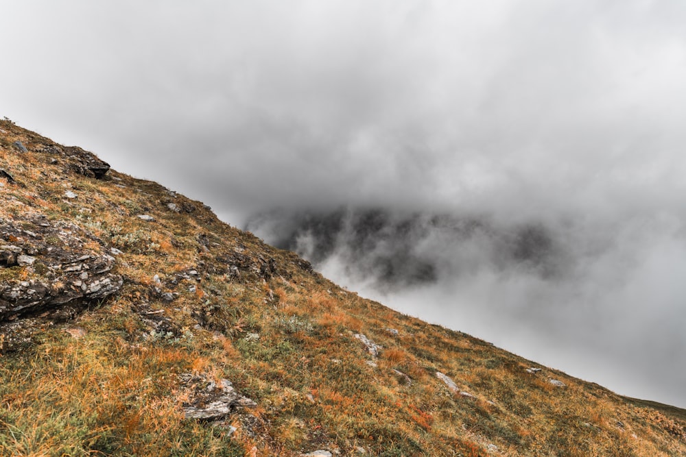 a hill with grass and rocks under a cloudy sky