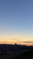 A peaceful sunset view over a city skyline with a mosque silhouette in the foreground.