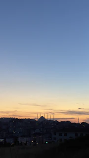 A peaceful sunset view over a city skyline with a mosque silhouette in the foreground.