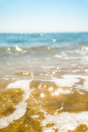 Close-up of a gentle ocean wave under a clear blue summer sky.