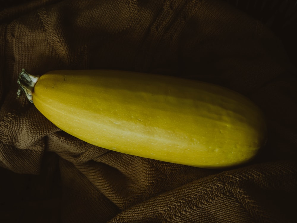 Una calabaza amarilla sentada encima de una tela marrón