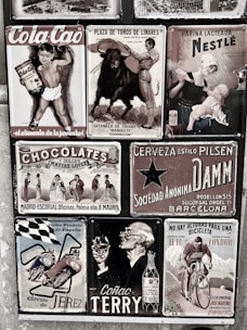 A collage of vintage advertisements with various themes, including a boy holding Cola Cao, a bullfighting poster, a Nestlé advertisement featuring a mother and child, and other ads for chocolate, beer, motorcycles, cognac, and cycling. The style is retro, and the images are arranged on a textured wall, each with distinct graphics and typography.
