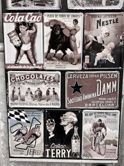 A collage of vintage advertisements with various themes, including a boy holding Cola Cao, a bullfighting poster, a Nestlé advertisement featuring a mother and child, and other ads for chocolate, beer, motorcycles, cognac, and cycling. The style is retro, and the images are arranged on a textured wall, each with distinct graphics and typography.