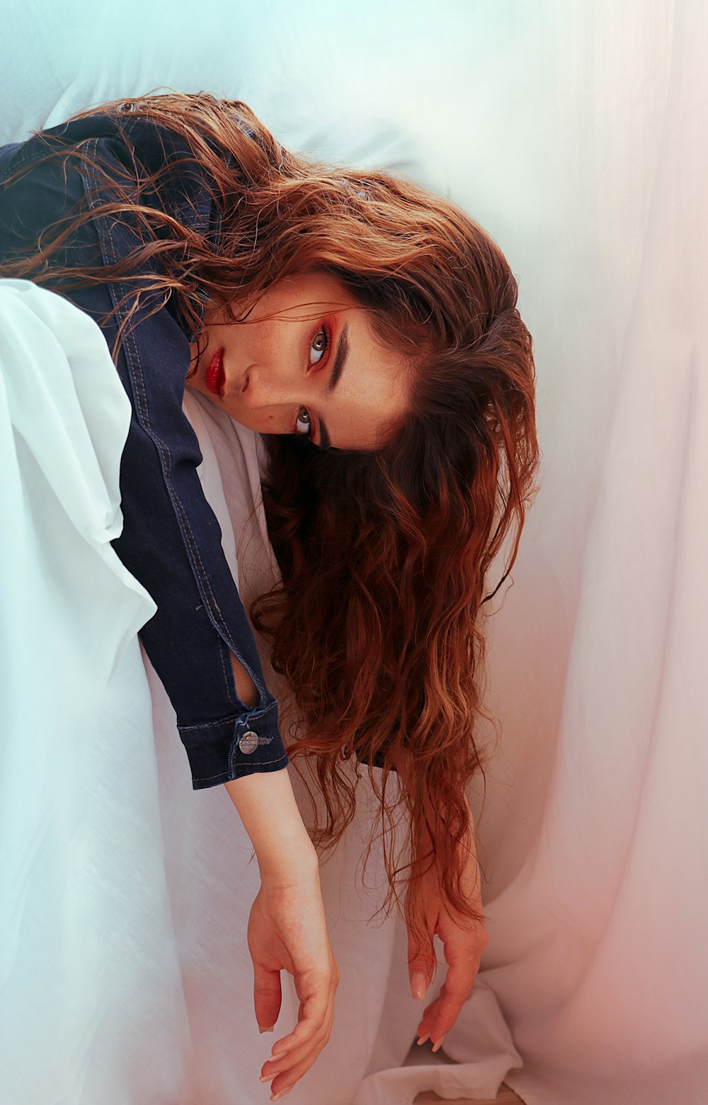 a woman with long hair laying on a bed