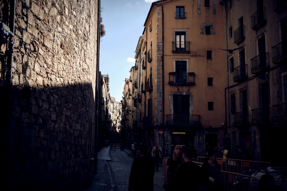 a group of people walking down a street next to tall buildings