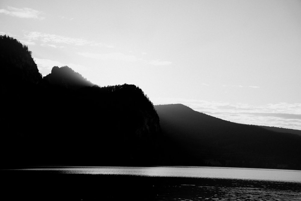 uma foto em preto e branco de uma montanha e um corpo de água