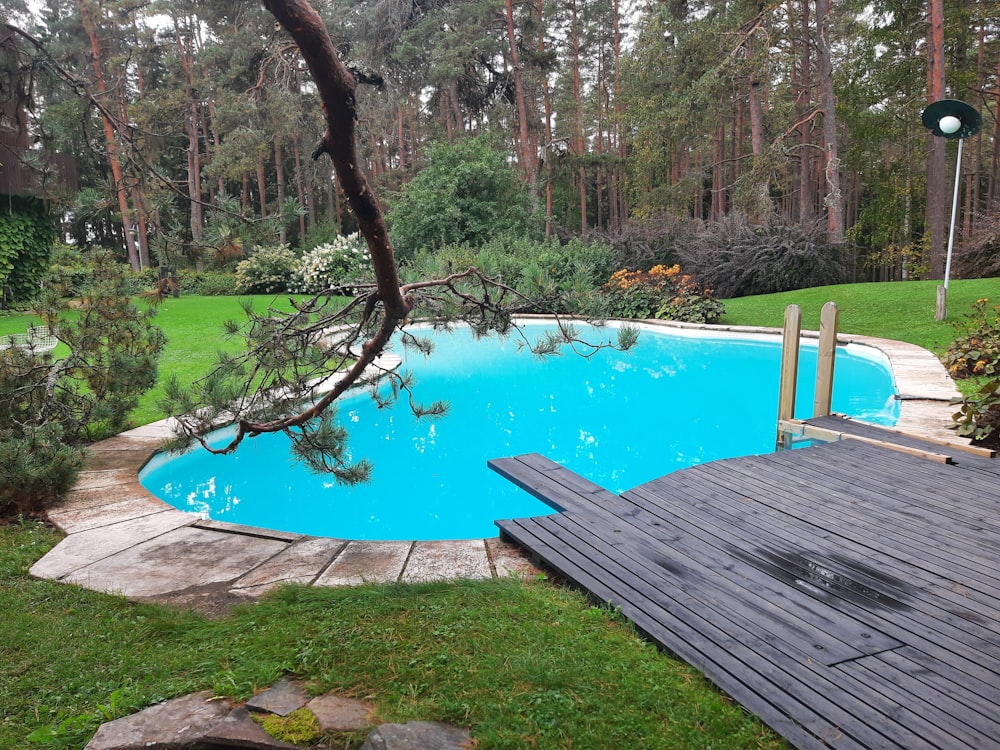 a wooden deck next to a pool surrounded by trees