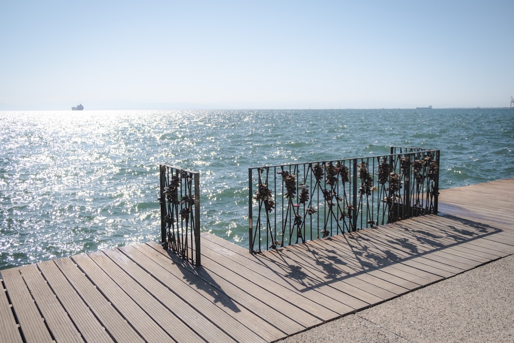 a metal fence sitting on top of a wooden pier next to the ocean