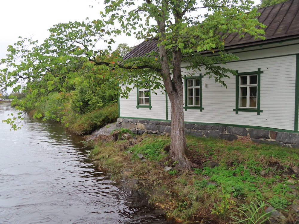 a small white house sitting next to a river