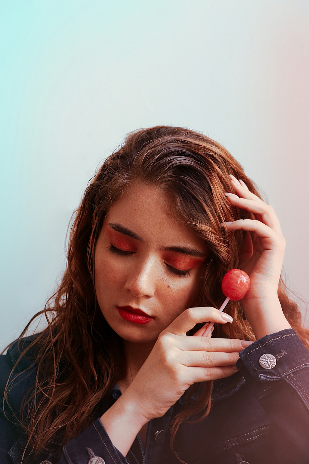 a woman with red eyes holding a cherry