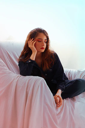 a woman sitting on a couch with her hand on her head