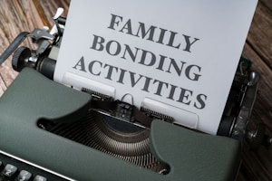 A vintage typewriter with a piece of paper inserted into it. The text 'FAMILY BONDING ACTIVITIES' is typed on the paper in large block letters. The typewriter is green and situated on a wooden surface.