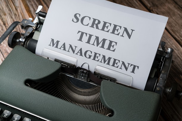 A vintage typewriter with a piece of paper inserted that reads 'Screen Time Management' in bold fonts. The machine sits on a wooden surface, suggesting an old or rustic setting.