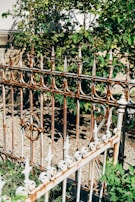 A metal garden fence with intricate design framing a blooming flower bed.