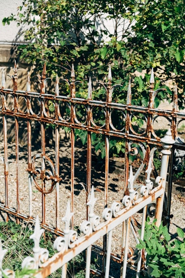 Rustic metal garden stakes with intricate designs standing tall in a lush green garden bed.