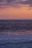 A serene ocean view just before sunset with gentle waves and a soft pink sky.