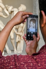 a man taking a picture of a statue with a cell phone