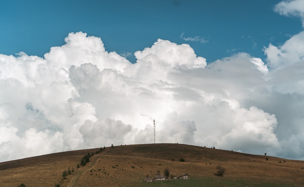 a hill covered in grass and clouds under a blue sky