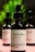 Three dark glass bottles with dropper tops, labeled as a skincare product containing Niacinamide 10% + Zinc. The central bottle is in focus, with a minimalist design and text emphasizing transparency in skincare. Blurred green foliage appears in the background.