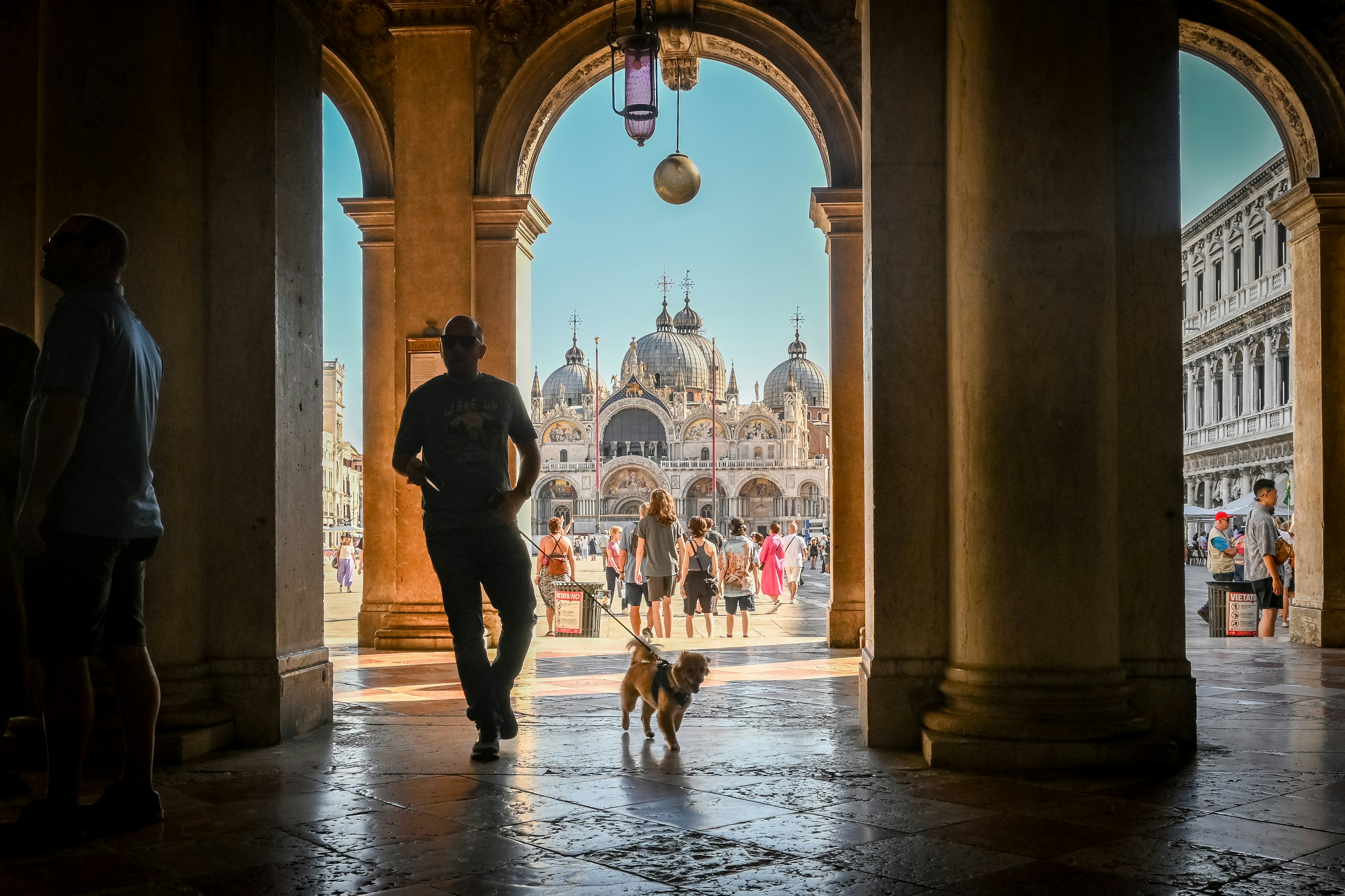 a man walking a dog through an archway