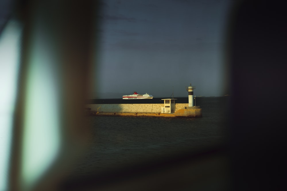 a view of a lighthouse and a cruise ship from a window