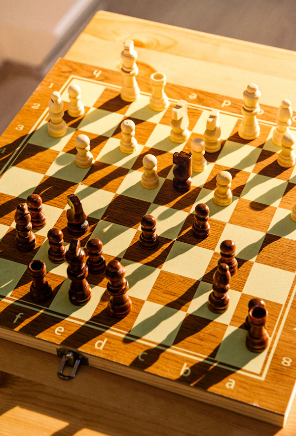 A wooden chess board set up with pieces