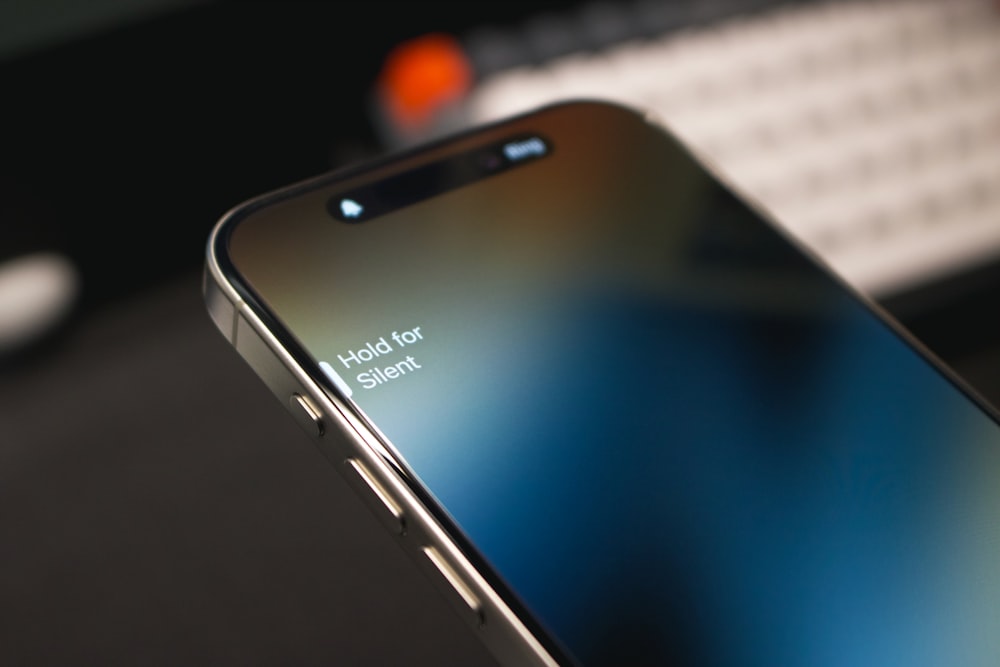 a close up of a cell phone with a keyboard in the background