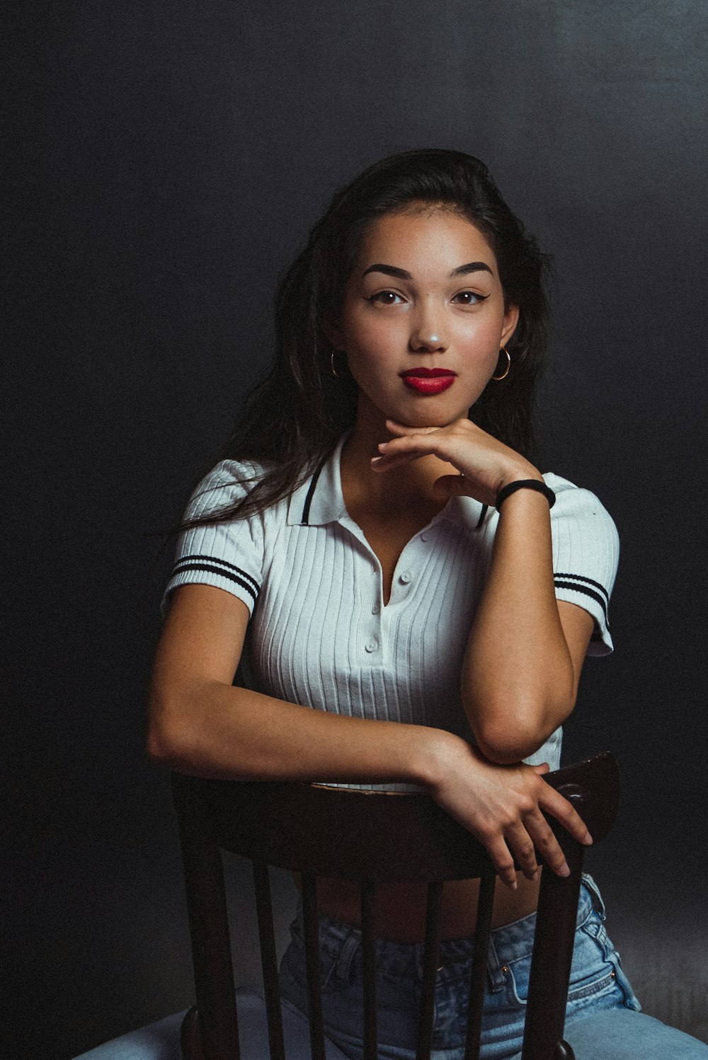 a woman sitting in a chair with her hand on her chin