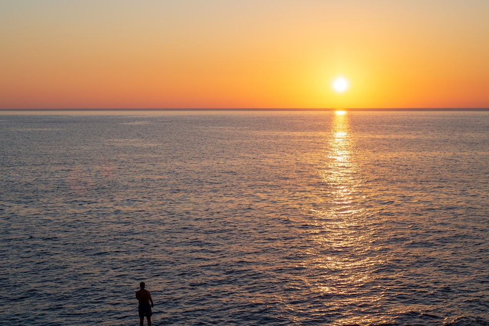 a person standing on a beach watching the sun set