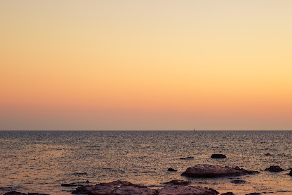 Un bateau solitaire est sur l’eau au coucher du soleil