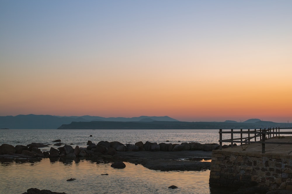 a bench sitting on top of a pier next to a body of water