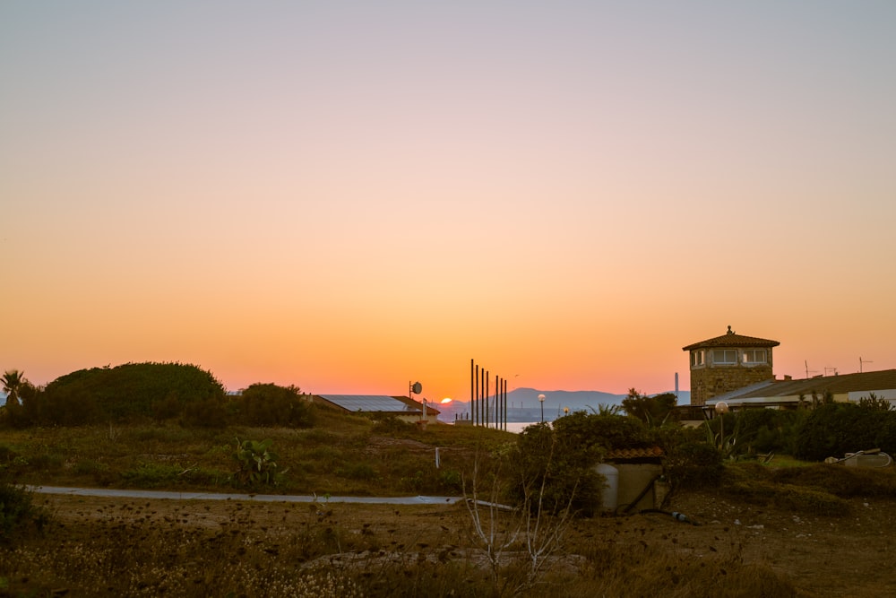 the sun is setting over the ocean with a lighthouse in the distance