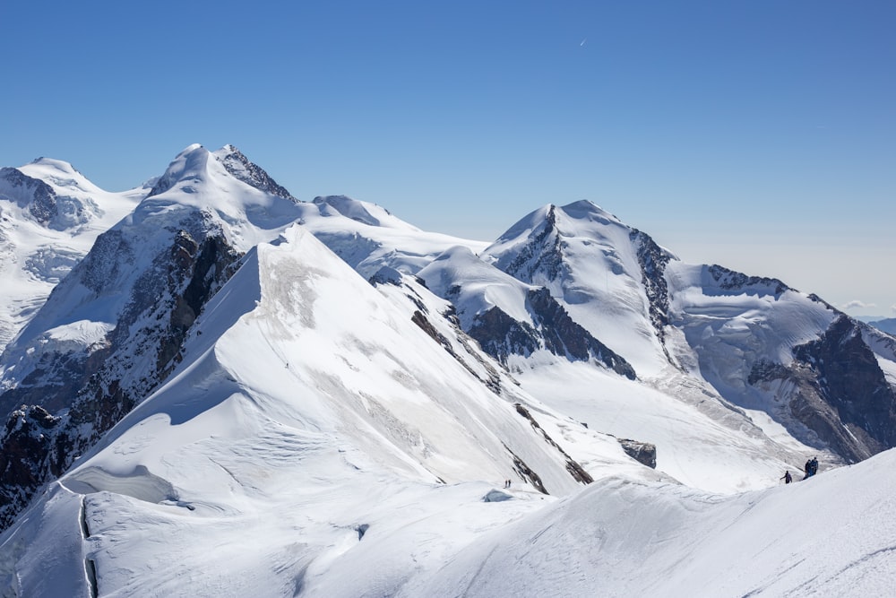 a group of mountains covered in snow under a blue sky