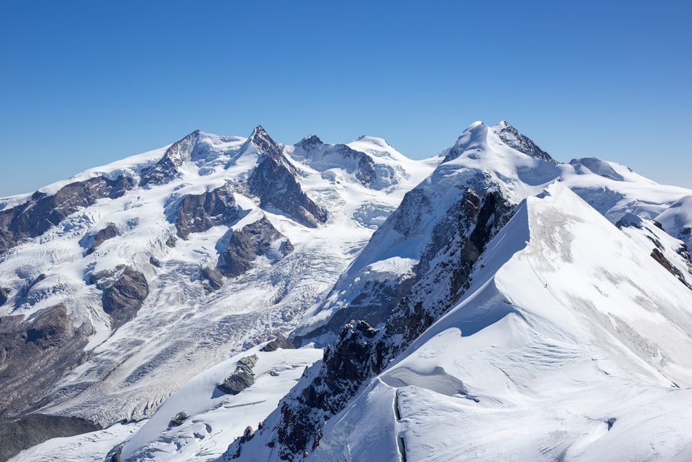 a mountain range covered in snow under a blue sky