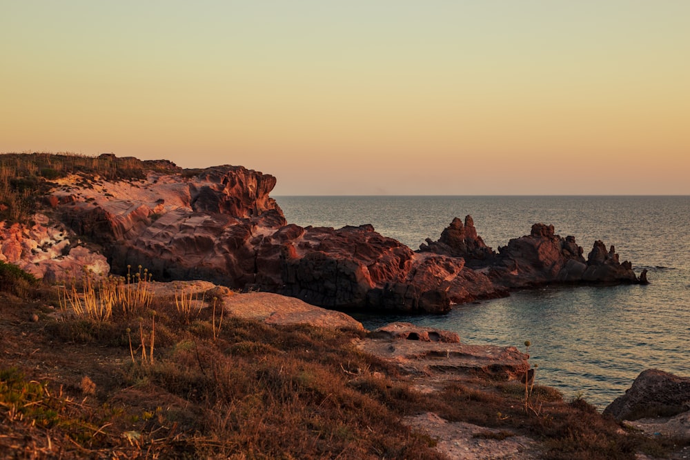 a body of water sitting next to a rocky shore