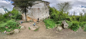 A small group practicing belaying techniques on a sunlit natural rock face.