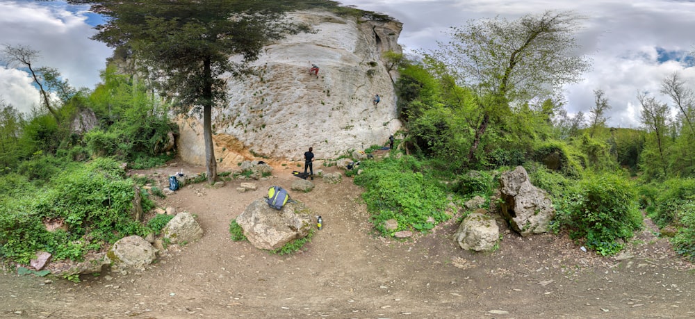 a group of people standing next to a large rock