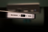 Close-up of a metallic device featuring a USB-C port flanked by speaker grills. The focus is sharp on the port while the background is blurred, suggesting an emphasis on technology and connectivity.