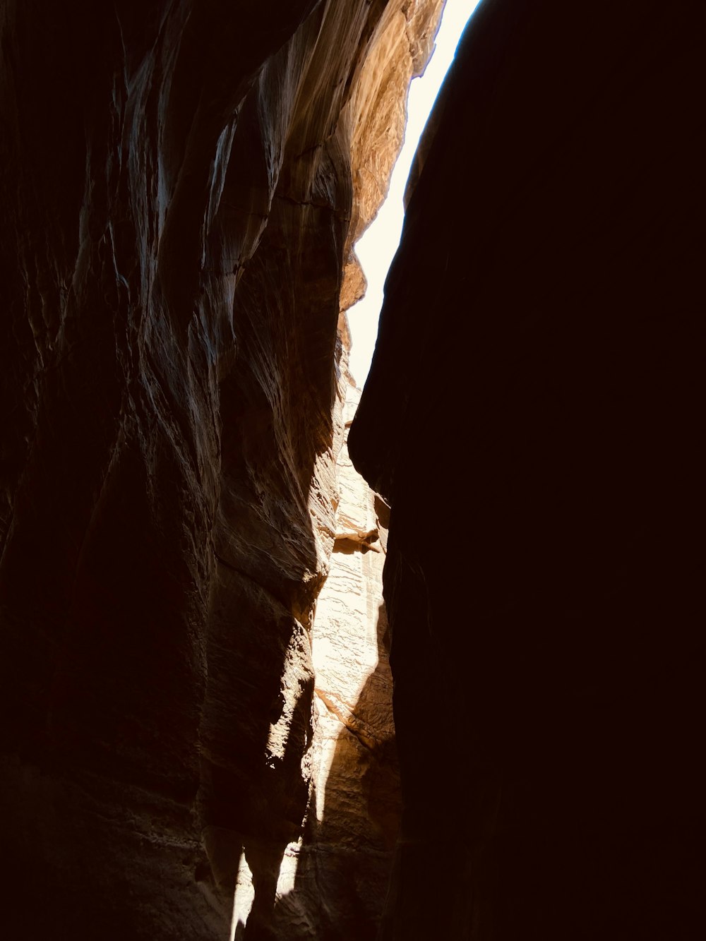 a person walking through a narrow slot in a cave