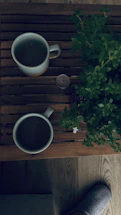 Cozy slippers resting beside a warm cup of tea on a wooden floor.