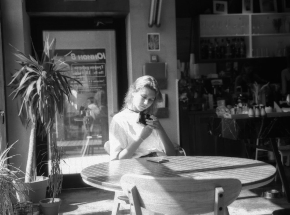 a woman sitting at a table using a cell phone