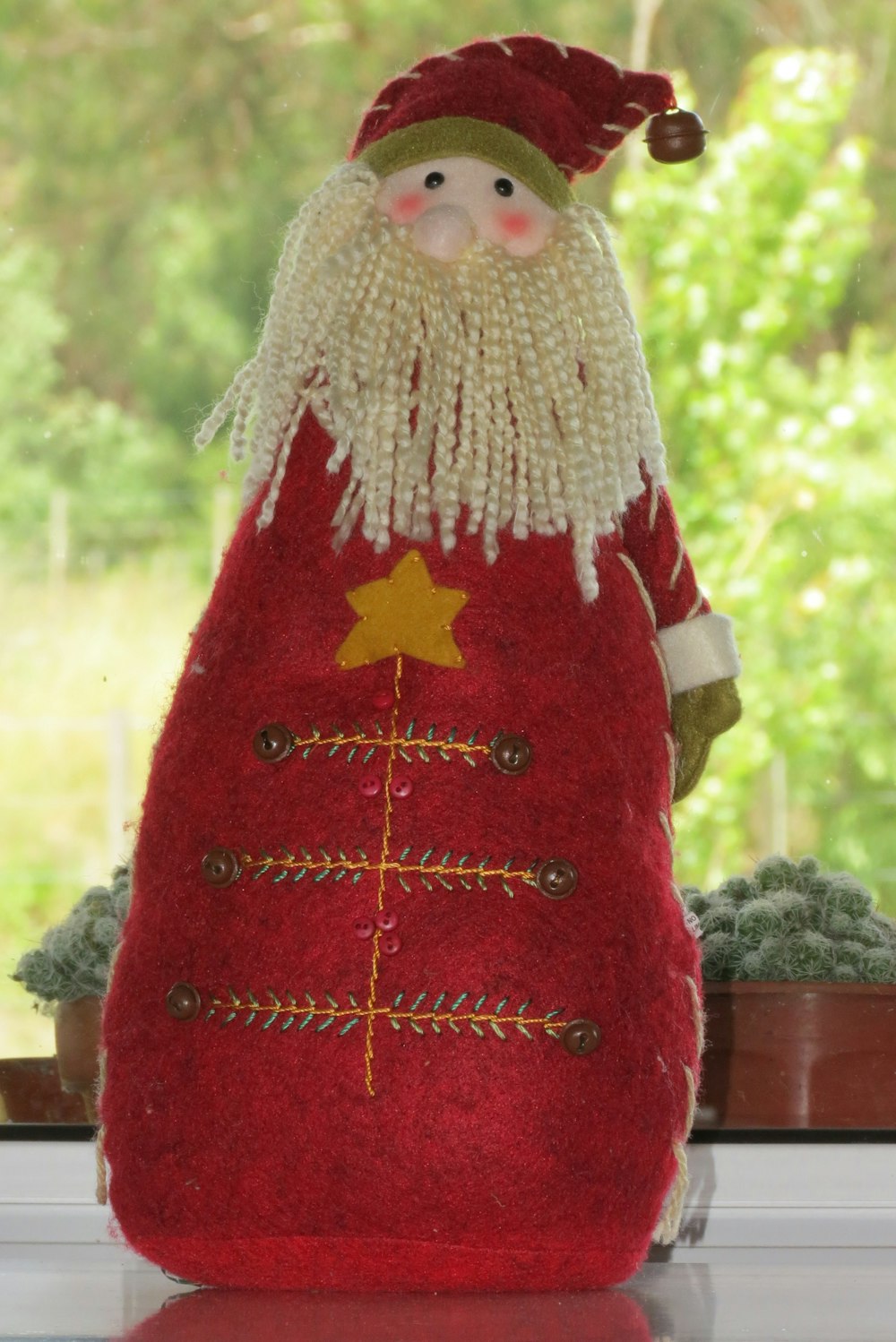 a red and white santa clause doll sitting on a window sill