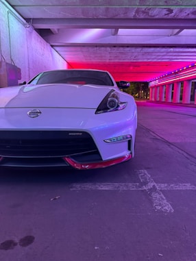 A sleek in-game car parked on a city street under neon lights.