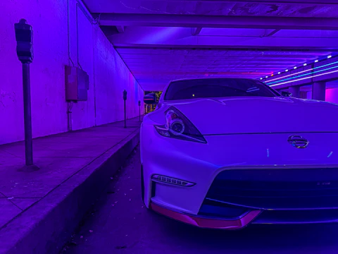 Phone frame showcasing a sleek car parking game with neon city lights background.