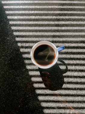 A warm cup of golden-hued coffee steaming gently on a rustic wooden table in a sunlit Madrid café.
