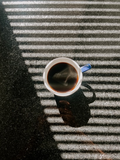 A warm cup of golden-hued coffee steaming gently on a rustic wooden table in a sunlit Madrid café.